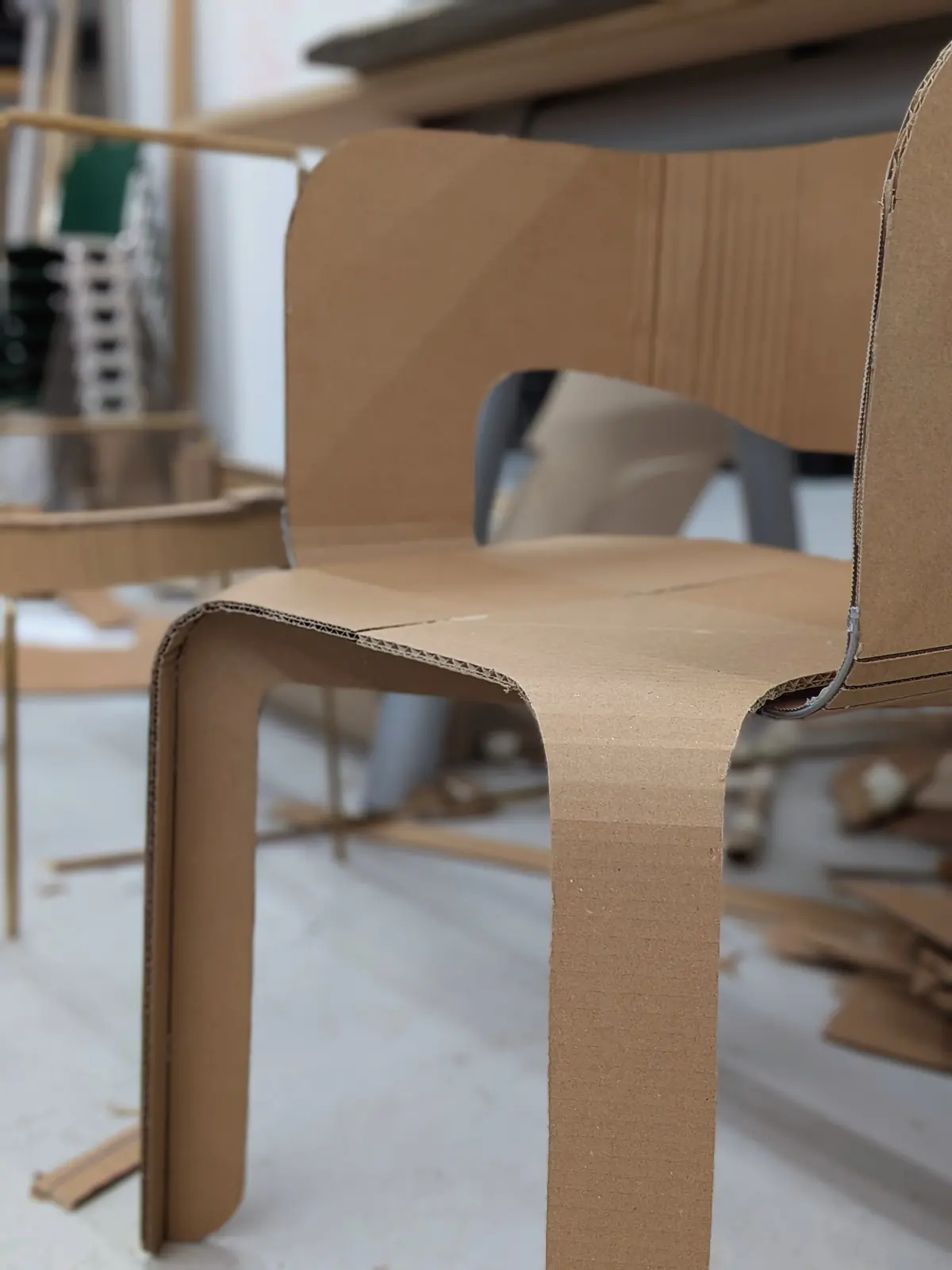 A cardboard model from the kickoff week, its seat and back stepping down in a cascade of simple folds.