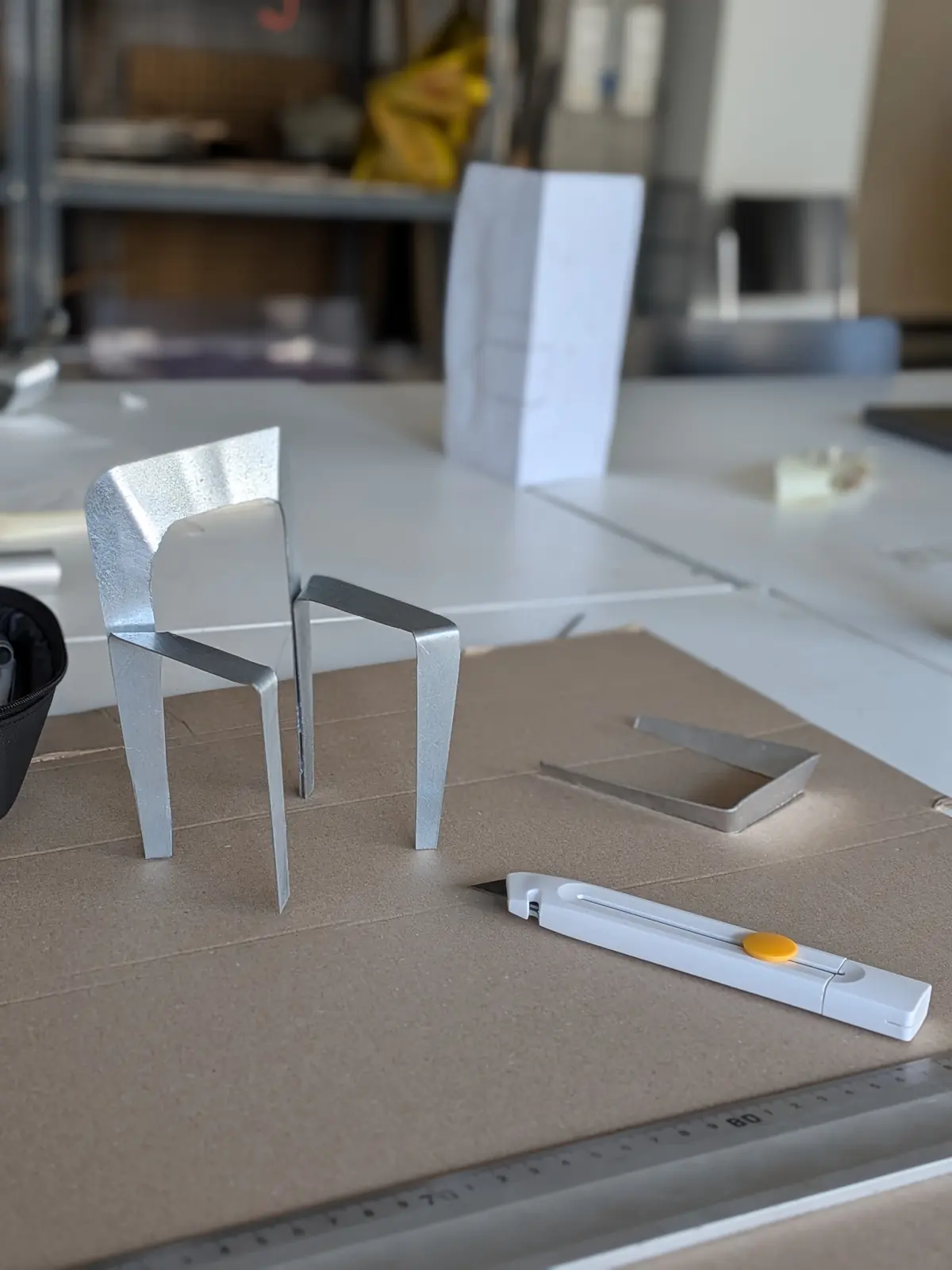 A small aluminium model with the legs bent at 45 degrees, standing on cardboard.