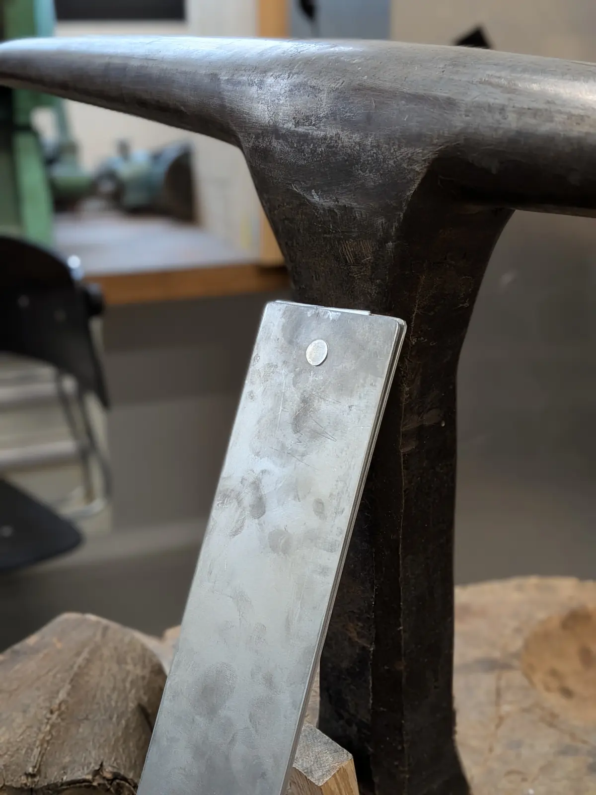 An aluminium rivet set through a strip of sheet, held in a vice.