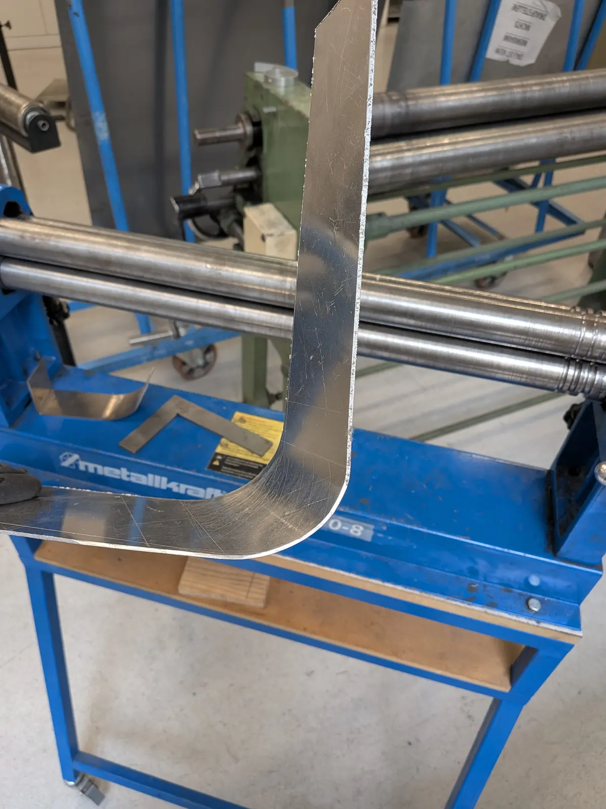 A 4 mm aluminium sheet being formed between the rollers of a bending machine.