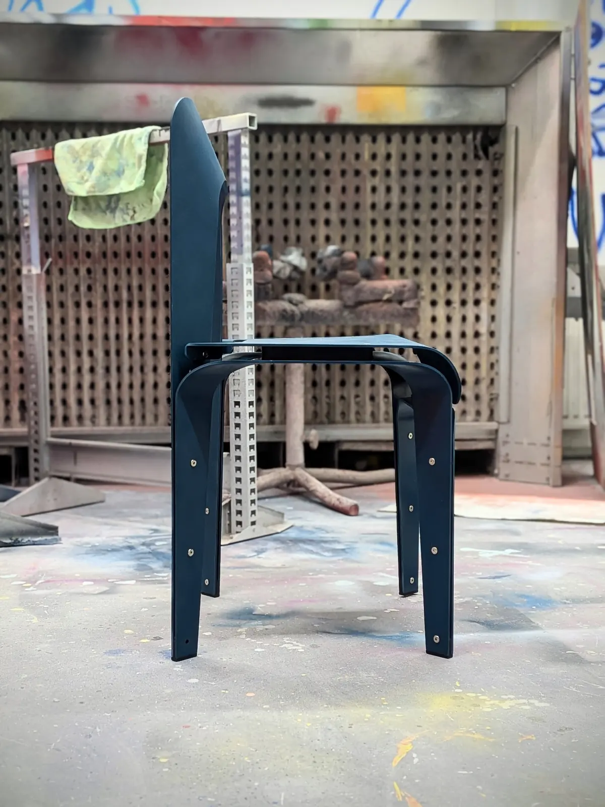 The chair in a spray booth after being coated deep blue-green.