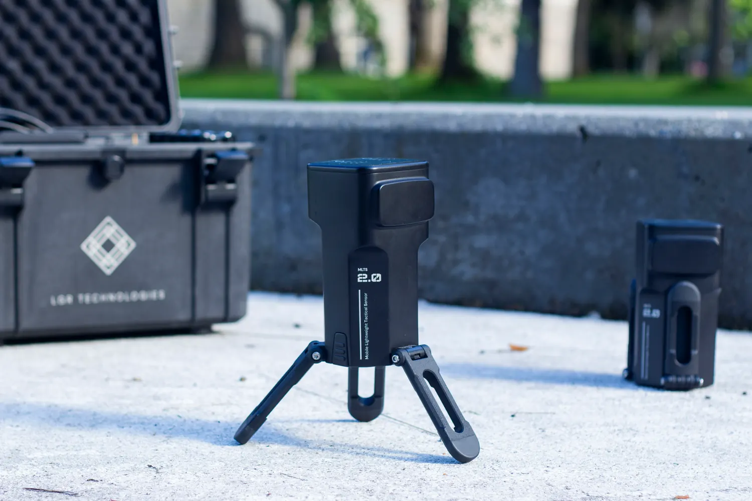 A unit standing on its legs on concrete beside its transport case.